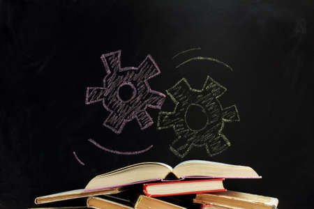 stack of different old books on the background of the mechanism drawn on the blackboard / search of the necessary knowledgeの写真素材