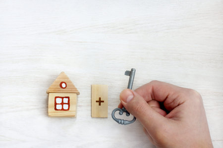 hand with key on a background of a wooden house / individual approach with a special solution