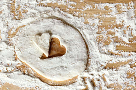 blank heart shape of farinaceous dough on a wooden table / cooking pastry for the holidayの写真素材