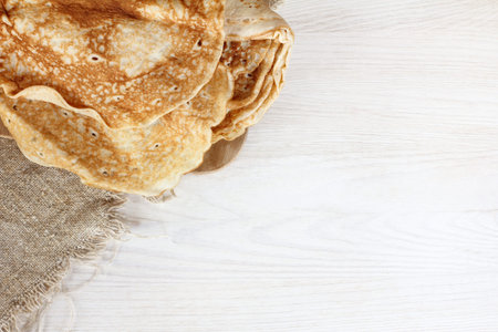 flat layout of a pile of pancakes on a light wooden table top view / lush appetizing breakfast