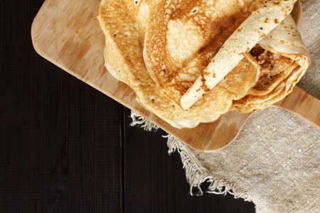 flat layout of a pile of pancakes on a dark wooden table top view / lush appetizing evening mealの写真素材