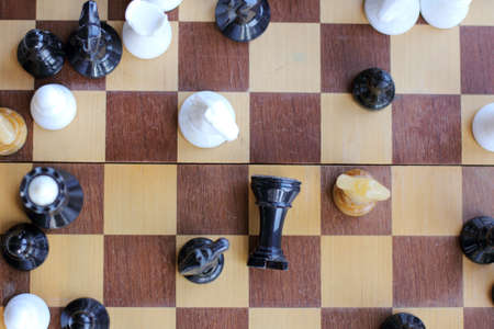 Black chess piece on the board fell, surrounded by three different horses, top view / unexpected denouement Partyの写真素材