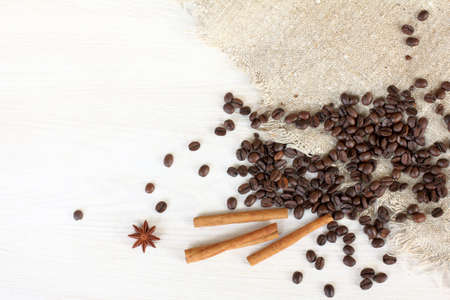 Flat layout with sacking and coffee beans scattered on the table with cinnamon sticks / special fragrant backgroundの写真素材
