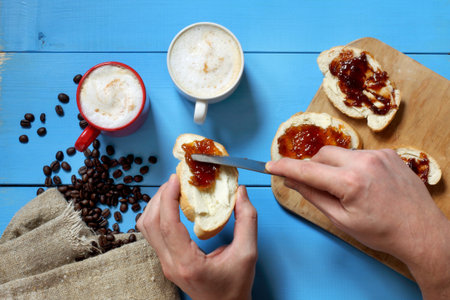 two mugs of foamy cappuccino and cooking toast with fruit jam, top view / breakfast for couplesの写真素材