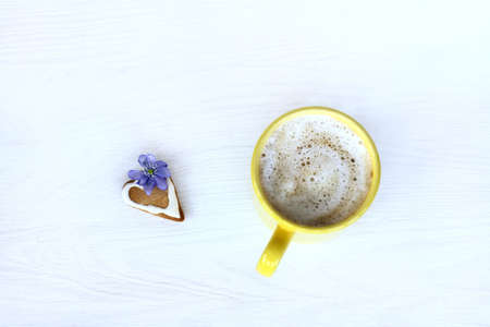 Foamy cappuccino in a yellow mug, with a gingerbread and spring flower top view/Favorite warming fragrant breakfastの写真素材