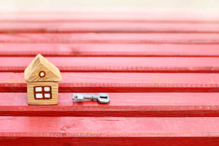 Small wooden house with a key on a red wooden surface / individual retro mansionの写真素材