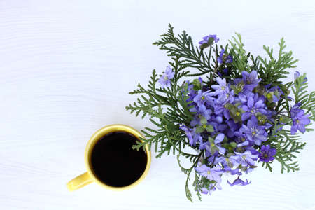bouquet of wild flowers with a yellow cup of black coffee view from above / the warming scent of springの写真素材