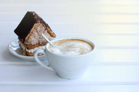 Foamy cappuccino in a cup on the background of baking in the form of a sweet house /Homemade coffee with moodの写真素材