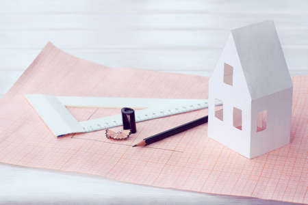 Paper layout of an apartment house with a pencil, ruler and a sharpener on a table / marking a plot for constructionの写真素材