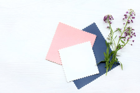 flat lay patterned cards with a bouquet of flowers on a white wooden table top view / background for...