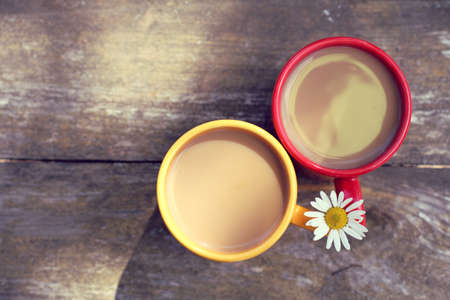 Coffee with cream in a red and yellow mug decorated with chamomile top view / summer coffee breakの写真素材
