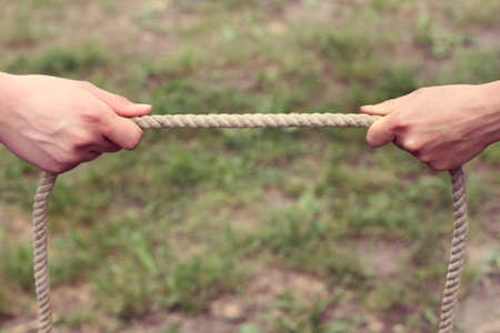 two hands holding a thick rope on different sides / one second before the confrontationの写真素材