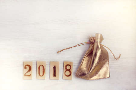 Wooden figures denoting 2018 and a golden bag on a light table top view/ holiday gift wrappingの写真素材