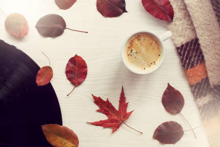 mug with coffee, leaves, vinyl plate on a light table top view / warming music of autumnの写真素材
