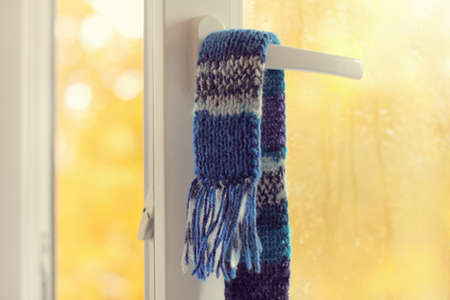 warm blue scarf hanging on the handle, an open window with drops after the rain / fresh air of autumn weatherの写真素材