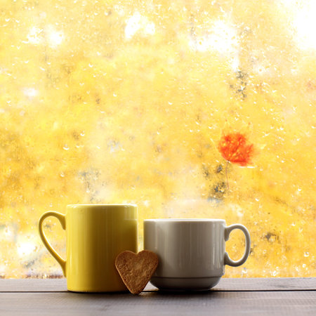two mugs with cookies in the shape heart on background  window after rain / hot autumn loveの写真素材