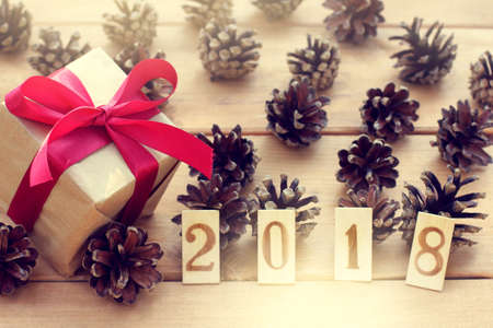 Festive gift with red ribbon is decorated with pine cones and a number indicating the coming year / greetings background 2018の写真素材
