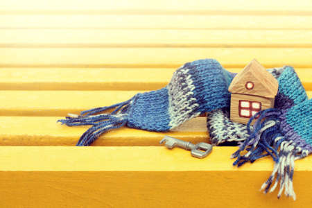 Layout wooden house is wrapped in blue scarf on the background yellow surface / environmental warming technologies for comfortable stayの写真素材