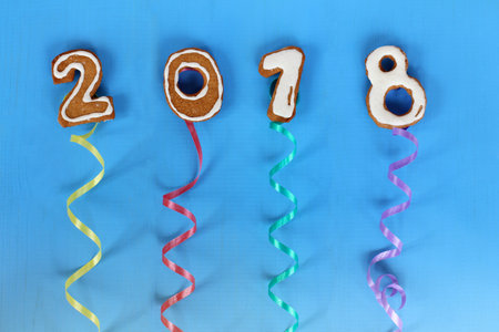 Date from ginger biscuits with glaze soar up on twirled multicolored ribbons, on a blue background/...