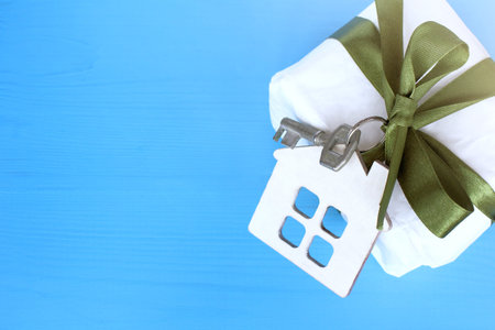 layout houses with key tied with green bow to gift on blue wooden background top view / complete refurbishment as giftの写真素材