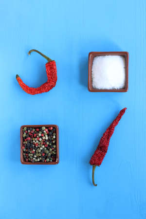 salt and different types of pepper on a blue table top view  spices for a particular tasteの写真素材
