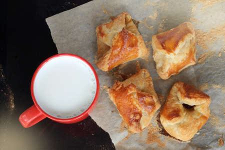 red cup with milk and baked delicious croissants on baking paper top view / pastries for breakfastの写真素材