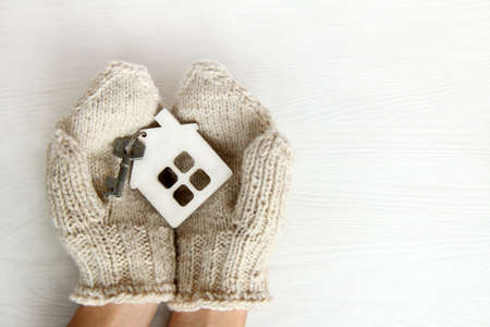 Symbol of the house with key in the hands dressed in warm mittens / cozy apartments for the winter holidaysの写真素材