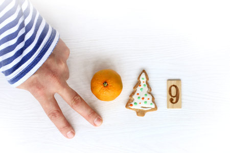 hand with a striped sleeve, mandarin, cookies Christmas trees and number nine / New Year concept...