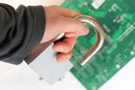 heavy padlock holds a hand in black clothes on a computer circuit background / access is opened