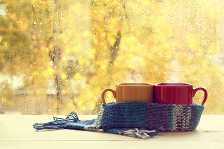 two cups in  blue scarf on table in the background of  window with drops after rain  warming autumn atmosphereの写真素材