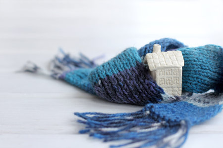 mock stone two-story house wrapped in scarf on light background  living in a warm atmosphere