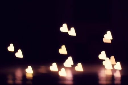 blurred lights in the shape of hearts on dark background / imagination of a romantic evening