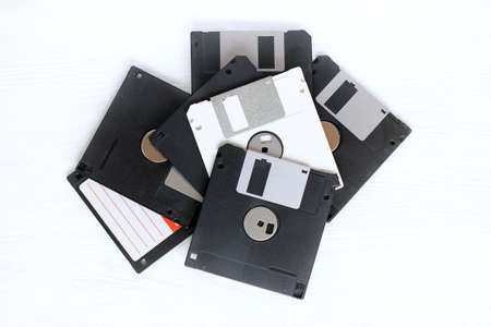 one white computer disk among a variety of dusty and old black media / information is not like everythingの写真素材