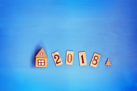 small house with light in a window next to figures and a tree on a blue background top view / use of...
