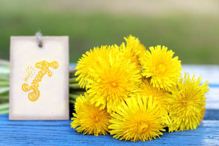 bouquet of yellow dandelions with a note, lie on a blue bench / hello summerの写真素材