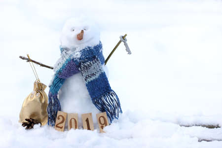 cheerful snowman in a scarf, holding a bag and a key on the background of a snowy background / open the winter season 2019の写真素材