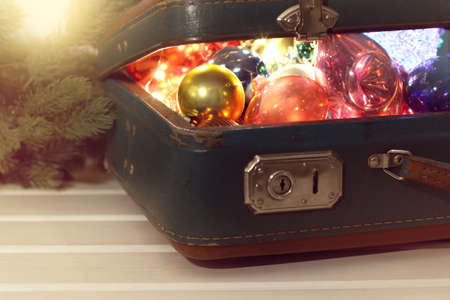 collection of glass Christmas decorations in an old suitcase on the table front view / holiday treasuresの写真素材