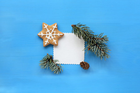 patterned empty blank decorated with a spruce branch and cookies on a blue background / place for...