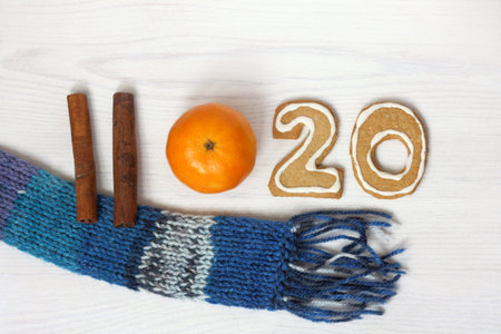cinnamon sticks, tangerine, curly cookies and a scarf top view / winter holidays 2020