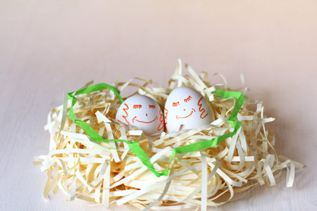 pair of chicken eggs with painted smiles lie in the nest. happy Easter holiday