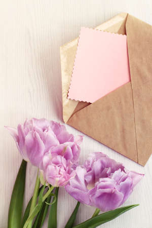 bouquet of tulips on the table next to the open envelope and a blank liner. background for holiday greetingsの写真素材