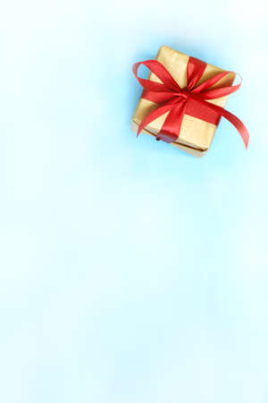 box wrapped in kraft paper with a red ribbon and bow on a white and blue background. gift for any holidayの写真素材