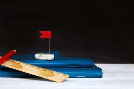 blue notebook and eraser wash with a red flag on the background of the school blackboard. towards...