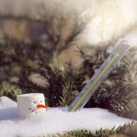 melting snowman under and a thermometer in a snowdrift under the sun in spring. oncoming of spring の写真素材
