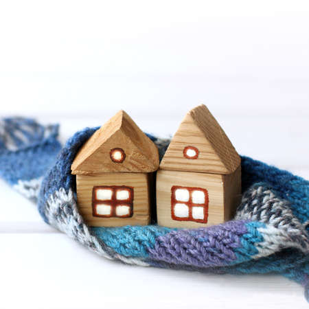 two wooden houses wrapped in a knitted scarf together. joint insulation solutions in constructionの写真素材