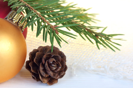 Christmas balls and pine cone under a fir branch on a background of blurry lights close-up....