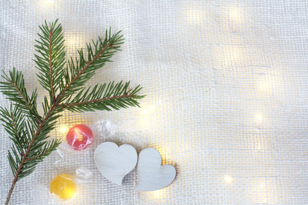 a pair of hearts and two candies next to a fir branch on the background of festive lights. love when...