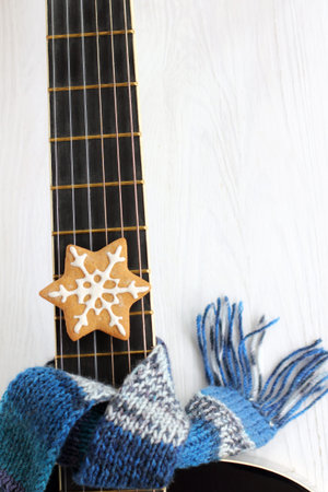 acoustic guitar in a blue scarf with cookies top view. warm melodies for the winter holidays