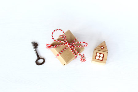 gift with a key and a house on a light surface top view. accommodation during the holidays