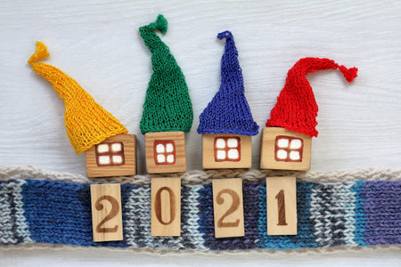 yellow, green, blue, red hats are worn on wooden houses standing on a knitted scarf. warming...